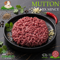 Raw ground meat mince presented on a black plate with branding text 'IKHLAS HALAL BUTCHER' and 'MUTTON MIX MINCE' on a dark textured background, surrounded by parsley, garlic, cumin seeds, peppercorns, and a red chili.