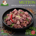 Raw mutton shoulder with bones cut into cubes, presented in a black bowl on a dark stone surface. The meat is garnished with a red chili pepper, minced garlic, and herbs, with scattered spices around it.