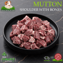 Raw mutton shoulder with bones cut into small cubes, displayed in a black bowl on a dark marble surface. The image includes branding for 'Iqbal Halal Butcher' and promotional badges.
